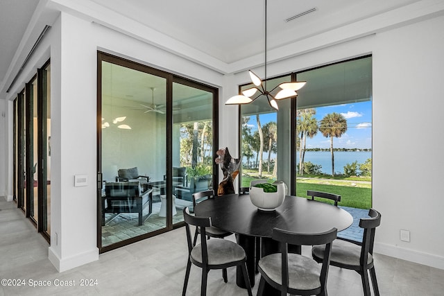 tiled dining room featuring a notable chandelier and a water view