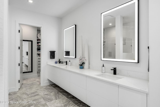 bathroom with tile patterned flooring, double sink vanity, and a tile shower