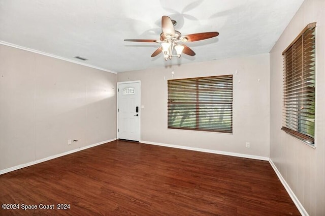 empty room with crown molding, dark wood-type flooring, and ceiling fan