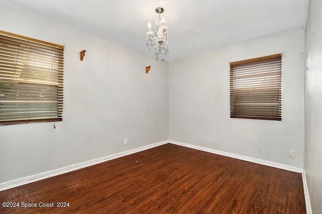 spare room featuring dark hardwood / wood-style floors and an inviting chandelier