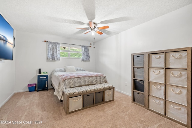 carpeted bedroom featuring ceiling fan and a textured ceiling