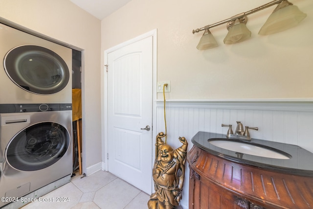 laundry room featuring light tile patterned floors, stacked washing maching and dryer, and sink