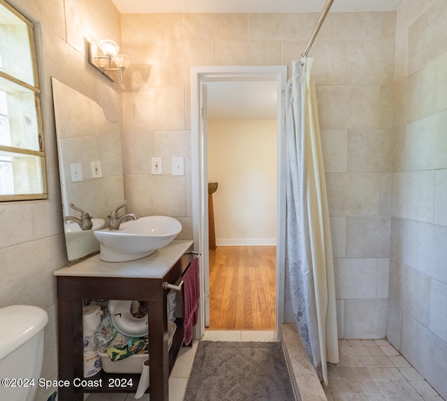 bathroom with hardwood / wood-style flooring, walk in shower, and tile walls