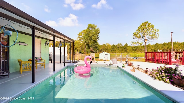 view of pool with a shed and a patio area