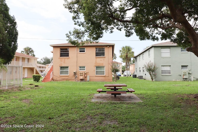 rear view of property featuring cooling unit and a lawn