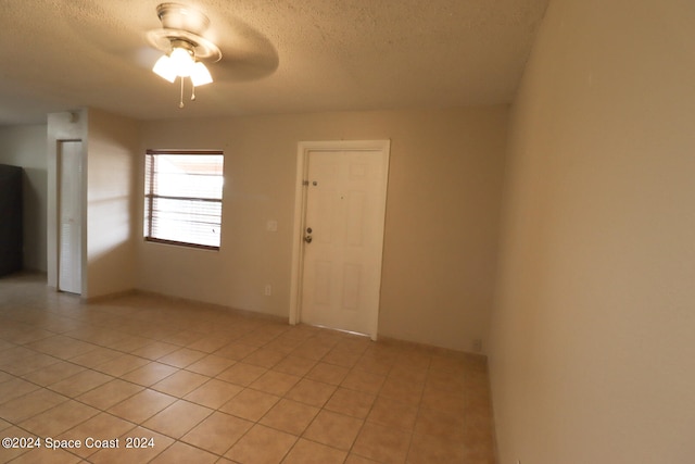 unfurnished room featuring a textured ceiling, ceiling fan, and light tile patterned floors