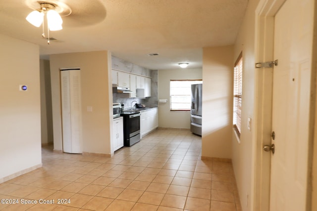 kitchen featuring light tile patterned floors, appliances with stainless steel finishes, decorative backsplash, ceiling fan, and white cabinetry