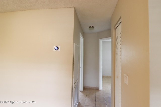 hall with light tile patterned floors and a textured ceiling