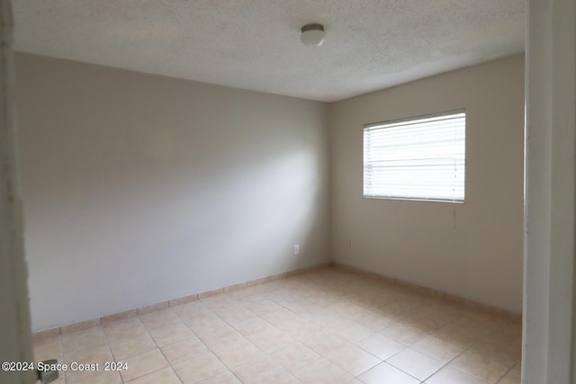 tiled empty room with a textured ceiling