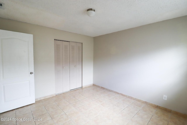 unfurnished bedroom with a textured ceiling, a closet, and light tile patterned floors