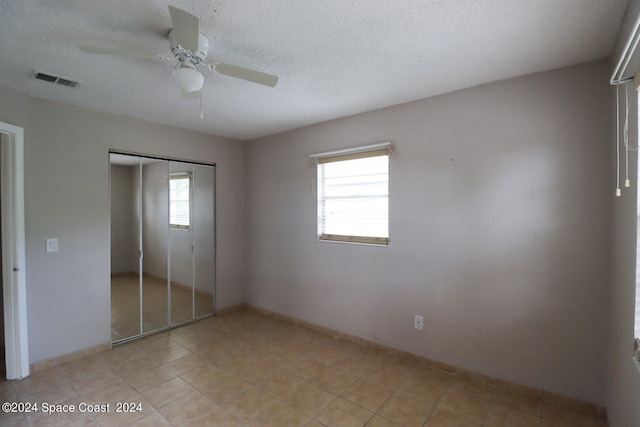 unfurnished bedroom with a closet, light tile patterned flooring, and multiple windows