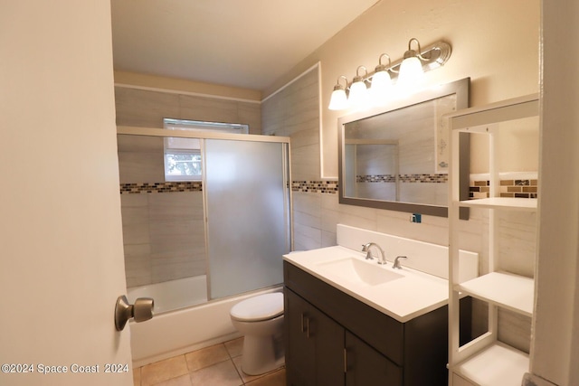 full bathroom featuring toilet, tile walls, tile patterned floors, enclosed tub / shower combo, and vanity