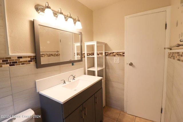 bathroom with tile walls, vanity, toilet, and tile patterned floors