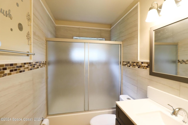 full bathroom with toilet, tile walls, bath / shower combo with glass door, and vanity