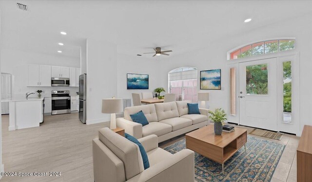 living room featuring ceiling fan, light hardwood / wood-style floors, and sink