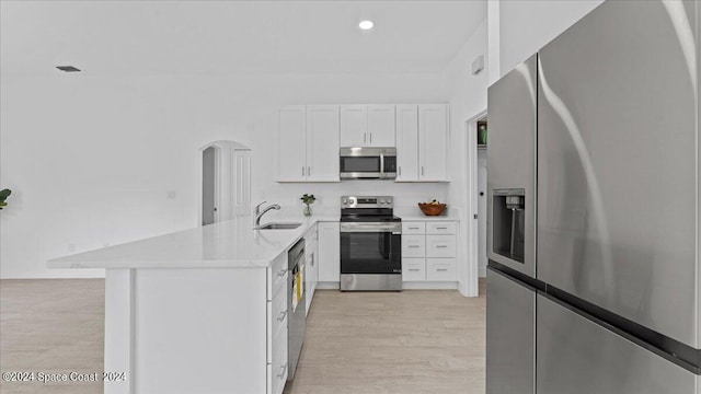 kitchen with light wood-type flooring, white cabinetry, kitchen peninsula, sink, and appliances with stainless steel finishes