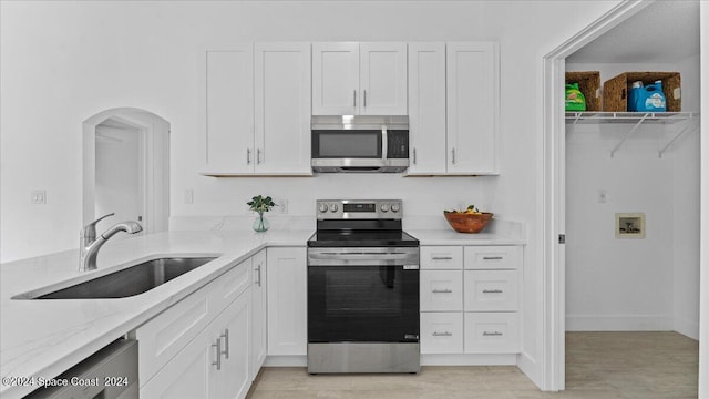 kitchen featuring sink, light stone countertops, appliances with stainless steel finishes, and white cabinetry