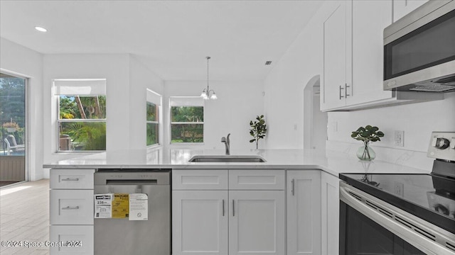 kitchen featuring light wood-type flooring, white cabinetry, stainless steel appliances, kitchen peninsula, and sink