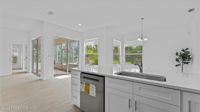 kitchen with pendant lighting, light hardwood / wood-style flooring, sink, light stone countertops, and stainless steel dishwasher