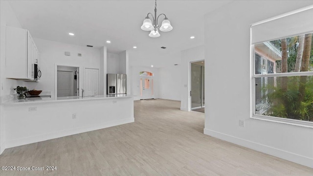 kitchen with stainless steel appliances, white cabinets, and light hardwood / wood-style floors