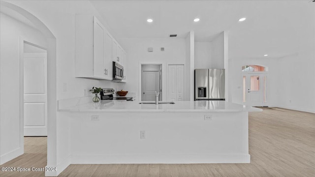 kitchen featuring light hardwood / wood-style flooring, appliances with stainless steel finishes, white cabinetry, sink, and kitchen peninsula