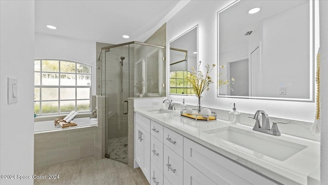 bathroom with plus walk in shower, hardwood / wood-style floors, and vanity