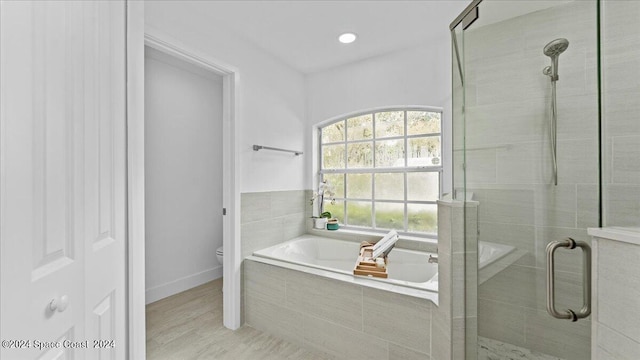 bathroom with separate shower and tub, toilet, and hardwood / wood-style flooring