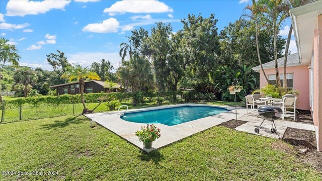 view of pool featuring area for grilling, a lawn, and a patio