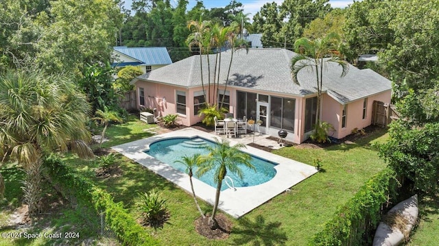 view of pool featuring a lawn, a patio area, and a sunroom