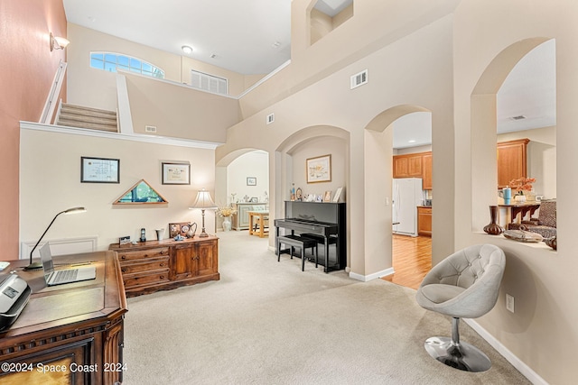 home office with light carpet and a towering ceiling