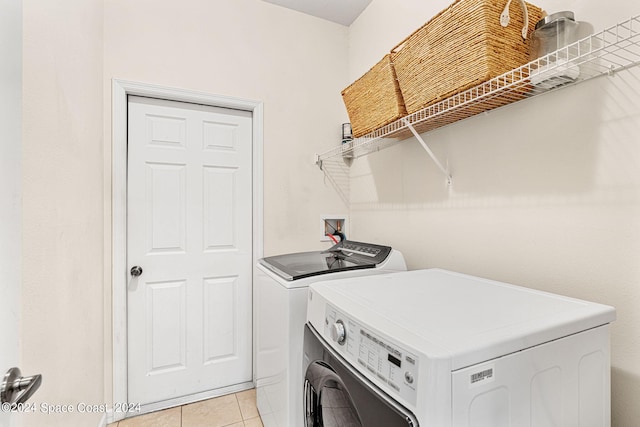 clothes washing area with independent washer and dryer and light tile patterned floors