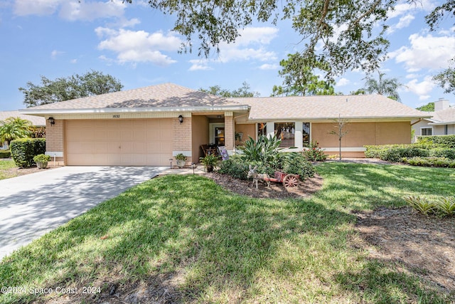 ranch-style house featuring an attached garage, driveway, a front yard, and brick siding