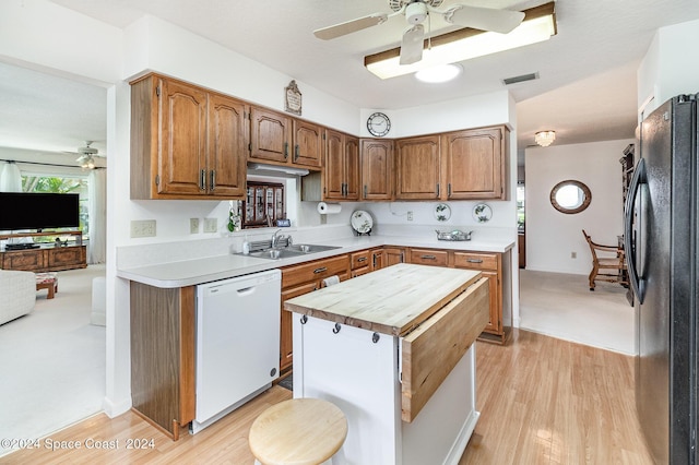 kitchen with visible vents, white dishwasher, freestanding refrigerator, and brown cabinets