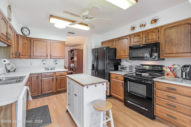 kitchen with brown cabinets, light countertops, a sink, and black appliances