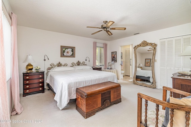 bedroom with ceiling fan, a textured ceiling, connected bathroom, light carpet, and a closet