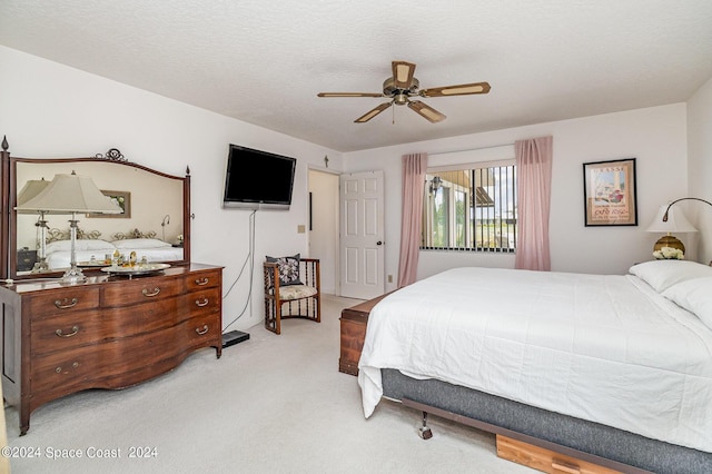 bedroom featuring light carpet, ceiling fan, and a textured ceiling