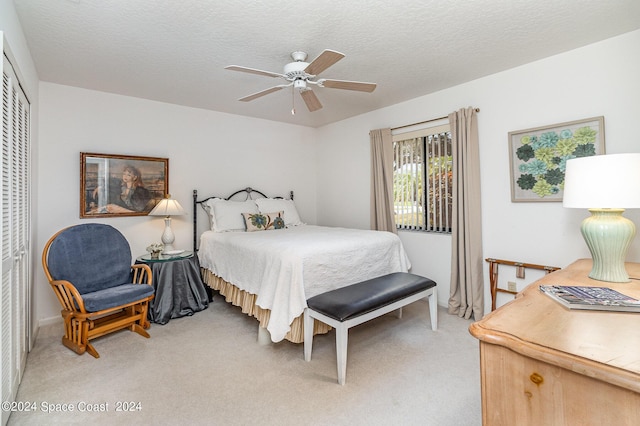 bedroom featuring light carpet, a textured ceiling, a ceiling fan, and a closet