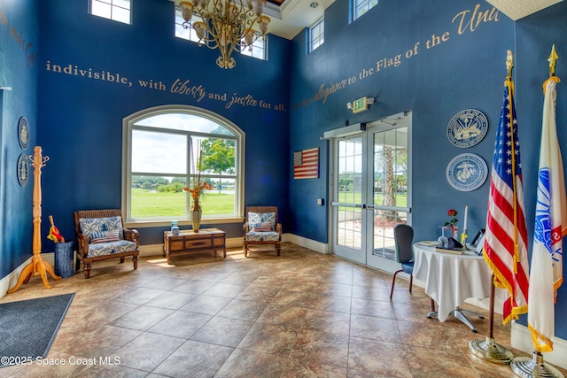 living area with a chandelier, french doors, plenty of natural light, and baseboards