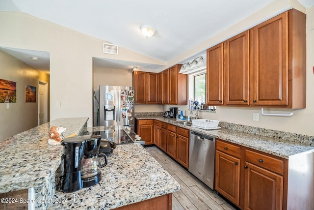 kitchen with light stone counters, appliances with stainless steel finishes, light wood-type flooring, and vaulted ceiling