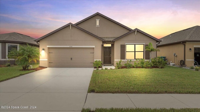 view of front facade featuring a garage, driveway, a lawn, and stucco siding