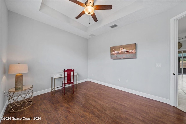 empty room featuring ceiling fan, a raised ceiling, and hardwood / wood-style flooring