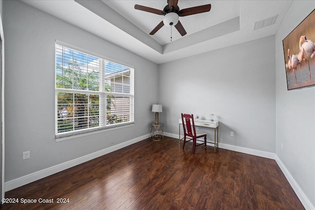 interior space with ceiling fan, a wealth of natural light, wood-type flooring, and a tray ceiling