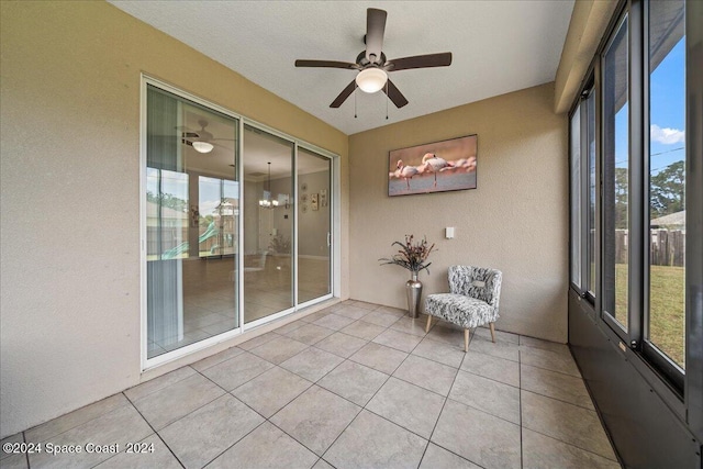 unfurnished sunroom featuring ceiling fan with notable chandelier