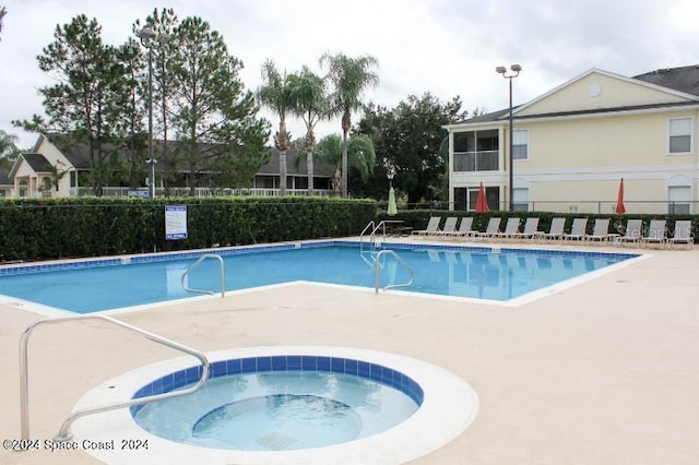 view of swimming pool featuring a patio area and a hot tub