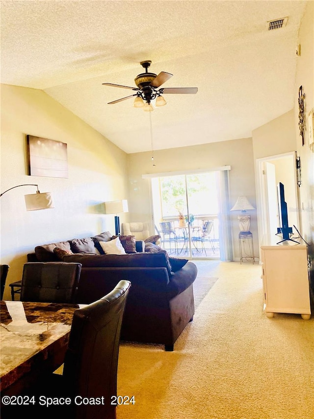 living room with ceiling fan, a textured ceiling, light carpet, and lofted ceiling