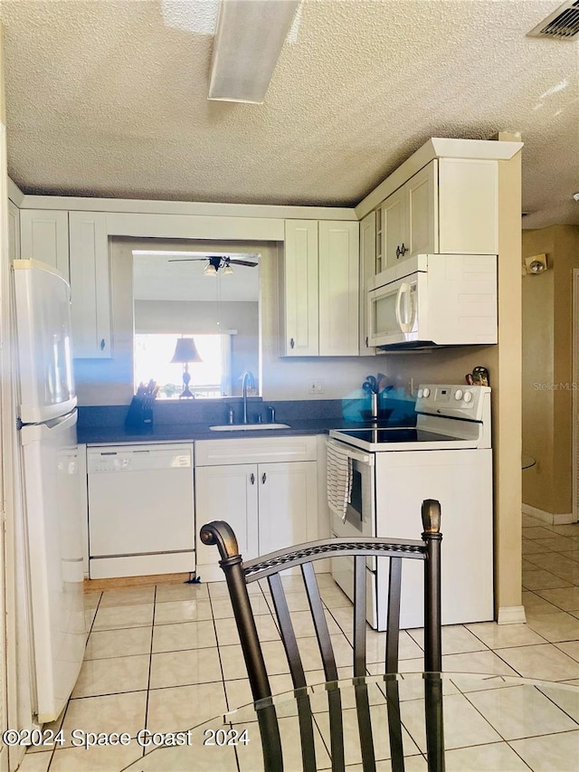 kitchen with sink, white appliances, a textured ceiling, ceiling fan, and white cabinets