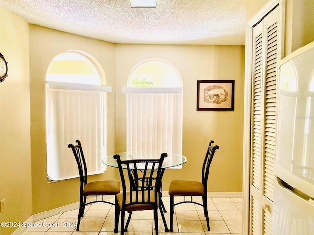 tiled dining space featuring a textured ceiling