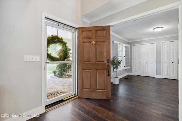 foyer entrance featuring a textured ceiling, dark hardwood / wood-style flooring, ornamental molding, and vaulted ceiling