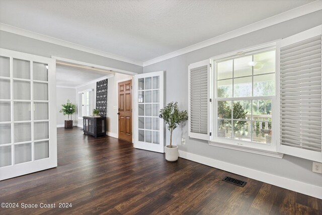 spare room featuring french doors, dark hardwood / wood-style floors, crown molding, and a textured ceiling