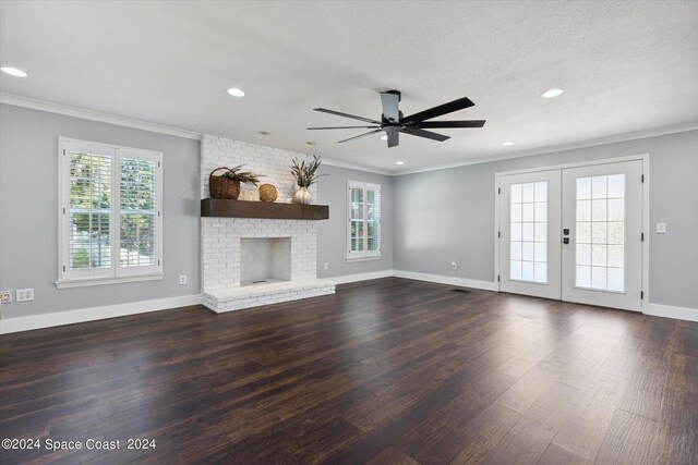 unfurnished living room featuring a textured ceiling, dark hardwood / wood-style flooring, a brick fireplace, ceiling fan, and crown molding